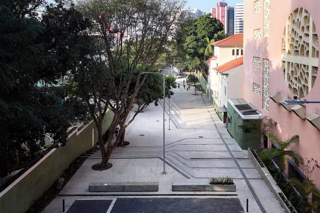 Paisagem urbana de Rio das Pedras SP, com via pública e prédios baixos arborizados, em enquadramento horizontal.