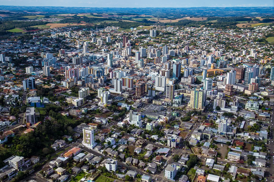 Vista aérea da cidade de Pato Branco, Paraná, mostrando áreas urbanas e verdes em um dia claro.