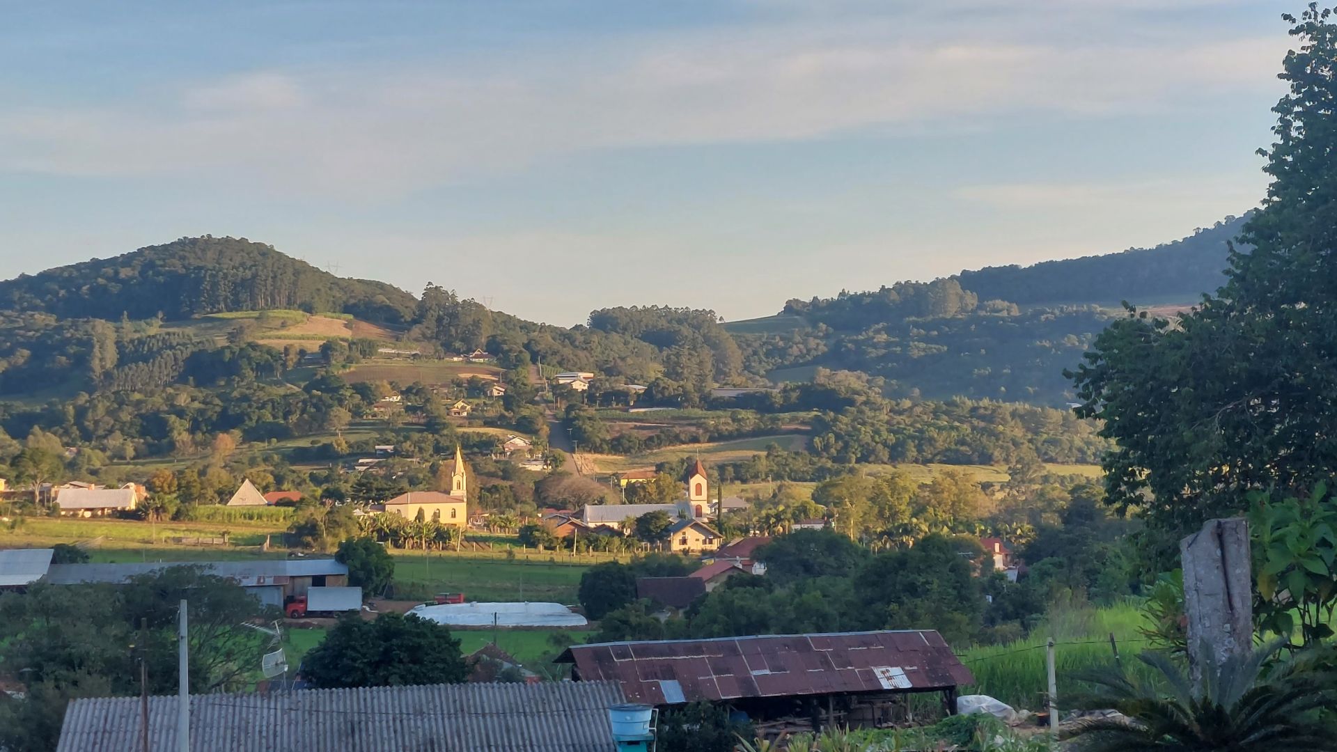 Vista de Presidente Lucena RS, com igreja e morros ao fundo