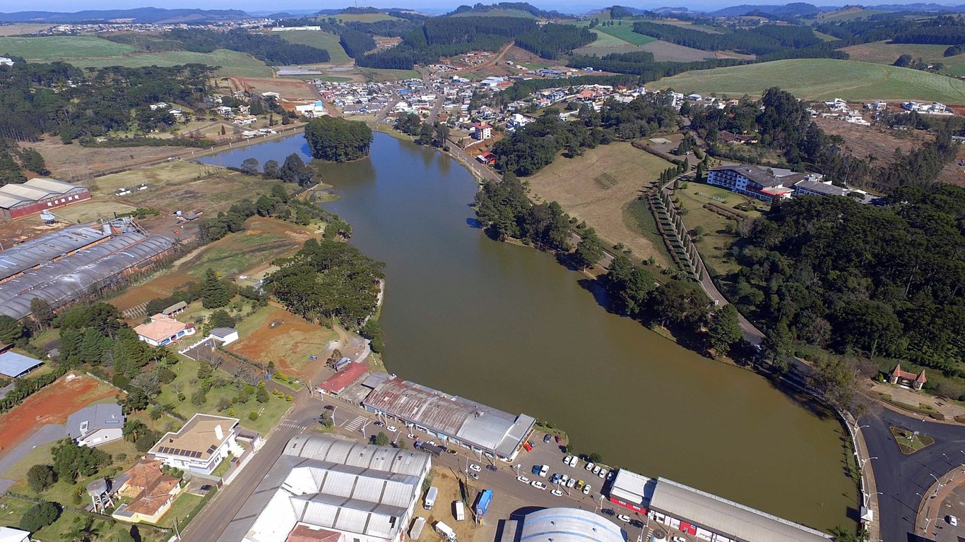 Vista aérea de Fraiburgo SC, com área urbana e pomares de maçã ao redor, em dia claro