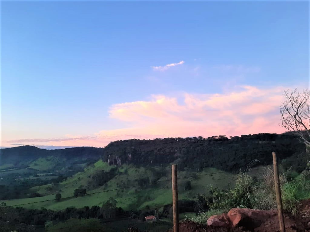 Paisagem rural de Minas Gerais, com morros verdes, estrada de terra e céu azul