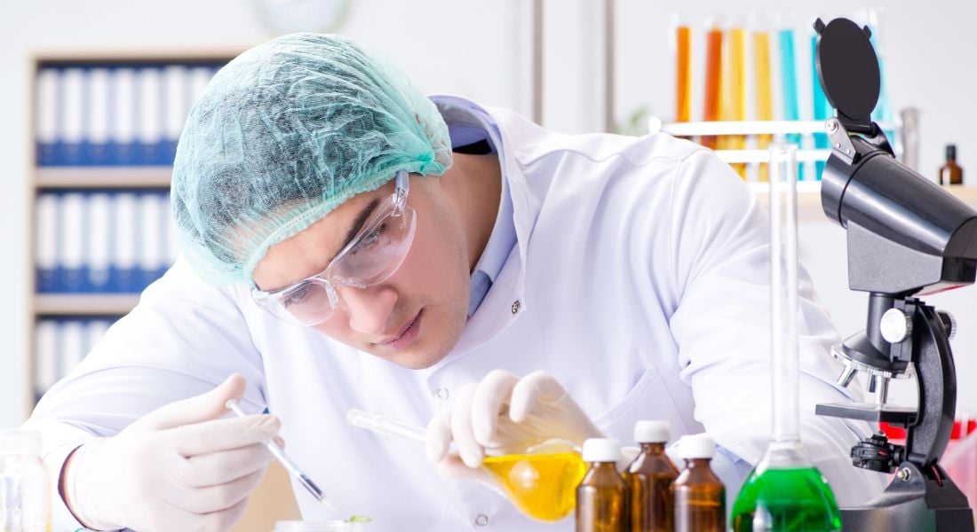 Profissional farmacêutico em inspeção de conformidade, usando prancheta e EPI em ambiente de laboratório