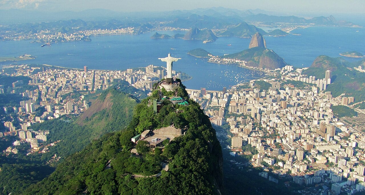 Vista aérea do Rio de Janeiro ao entardecer, com o Cristo Redentor ao fundo