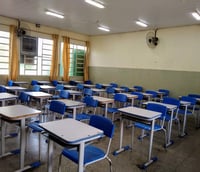 Sala de aula de escola pública brasileira, com carteiras azuis, em ambiente institucional e iluminado