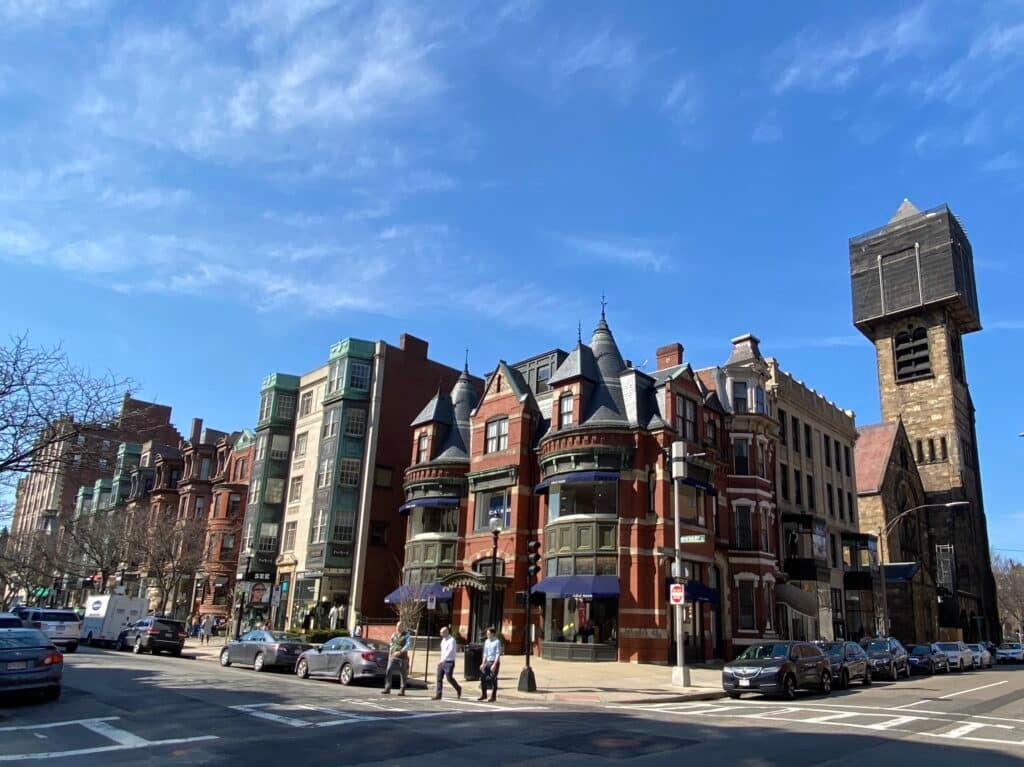 Campus universitário com prédios modernos; estudantes caminham em dia ensolarado.