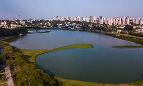 Paisagem urbana ilustrativa, com lago e área verde ao centro.