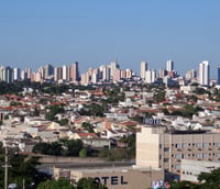 Paisagem urbana de Presidente Prudente SP, com áreas verdes e prédios ao fundo.
