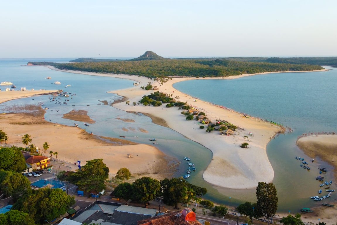 Vista aérea de Alter do Chão, em Santarém PA. Praia de água doce, barcos e tons de azul e verde do Rio Tapajós compõem a paisagem.