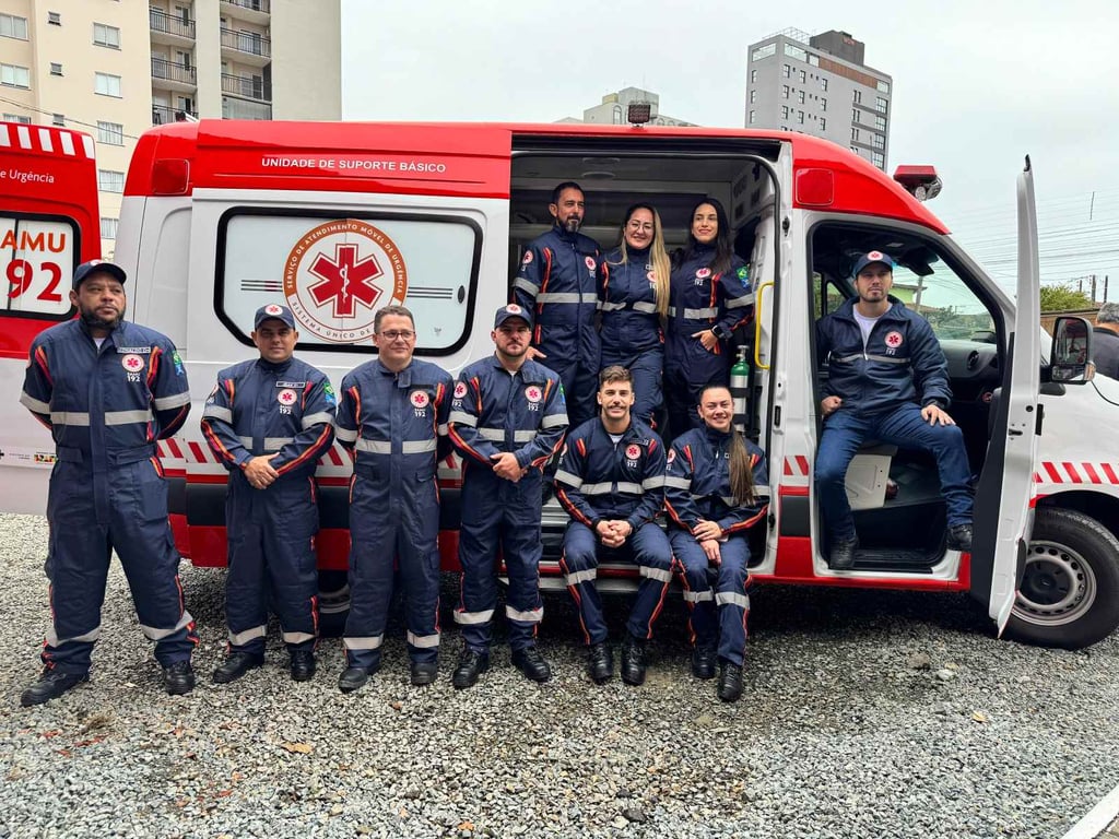 Profissionais do SAMU ao lado de ambulância, em ambiente urbano, em registro institucional