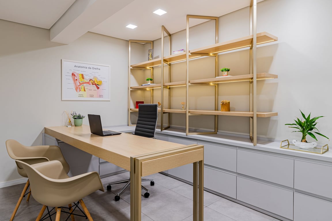 Ambiente de consultório de fonoaudiologia, bem iluminado e organizado, com materiais de atendimento em mesa.
