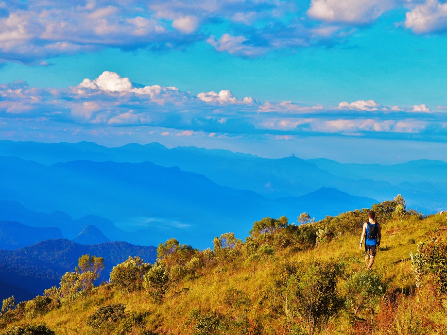 Paisagem do Vale do Paraíba ao pôr do sol, com morros e cidade ao fundo sob luz dourada
