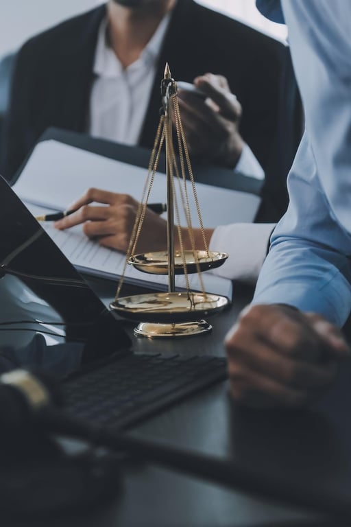 Ambiente jurídico com documentos, notebook e balança da Justiça ao fundo