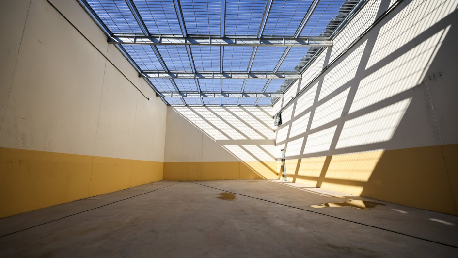 Ambiente interno institucional de unidade prisional, com pátio e iluminação natural; imagem horizontal e sóbria