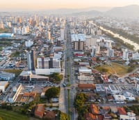 Vista aérea de Tubarão SC com o rio Tubarão e área urbana ao fundo em dia ensolarado.