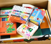 Materiais pedagógicos organizados, como lápis de cor e guache, em ambiente escolar.