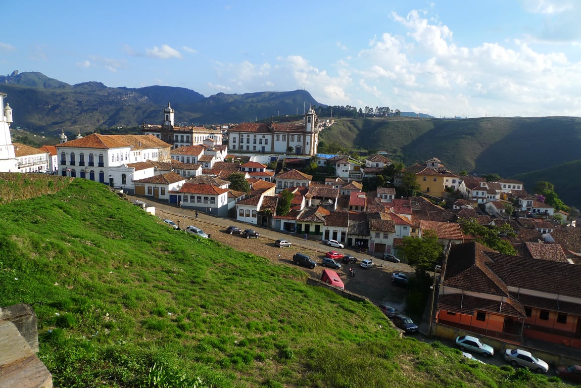 Vista aérea de cidade do Sul de Minas, com morros ao fundo e céu azul