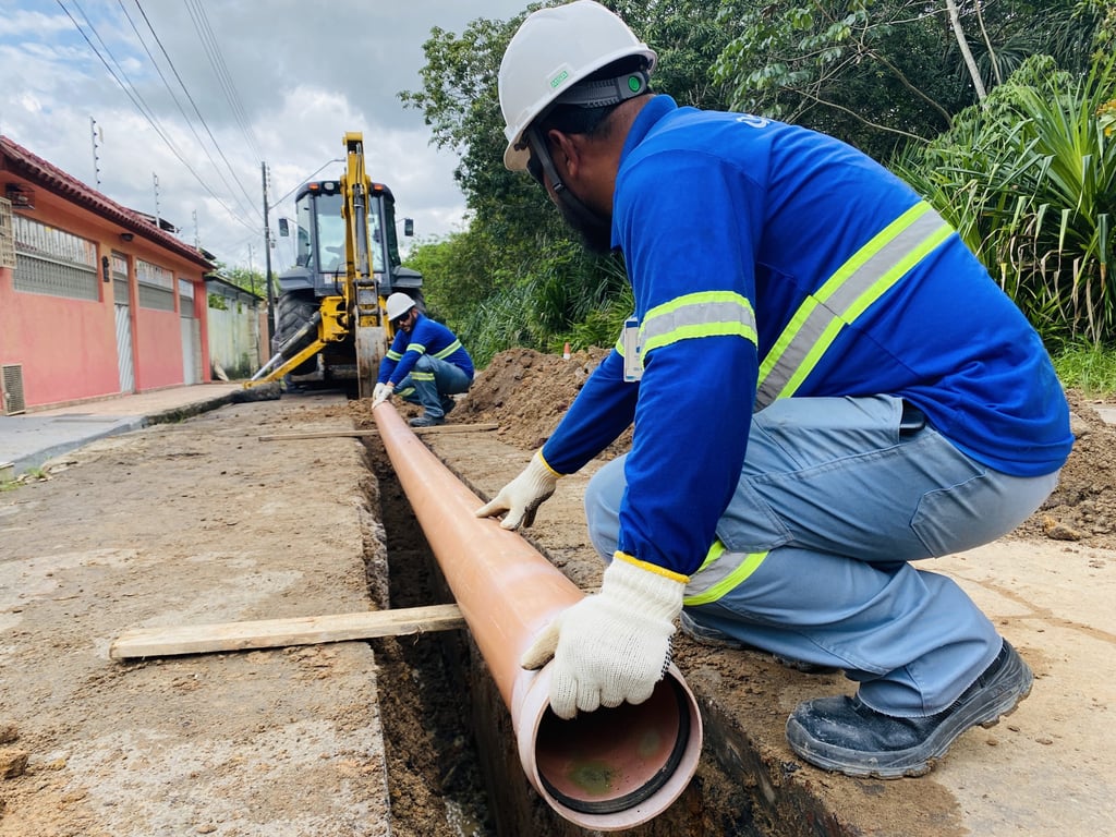 Trabalhadores de saneamento instalando tubulação em área urbana