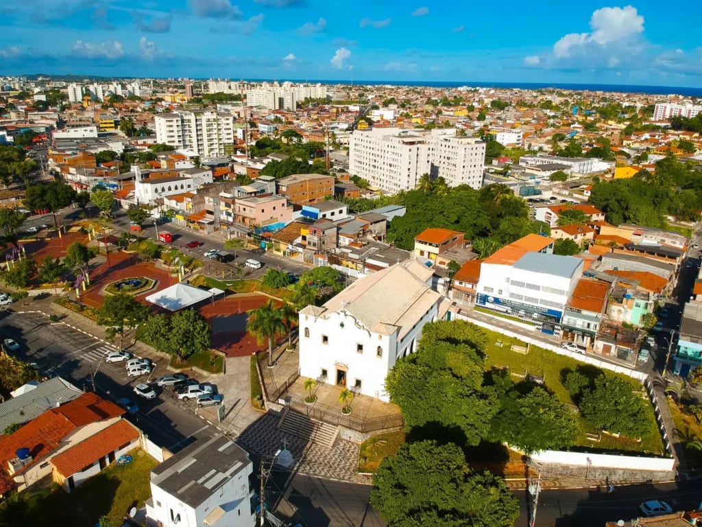 Vista aérea de cidade do interior do Nordeste com praça arborizada e prédios baixos