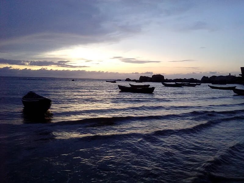 Paisagem costeira com barcos ao pôr do sol, representando o litoral piauiense e o Delta do Parnaíba