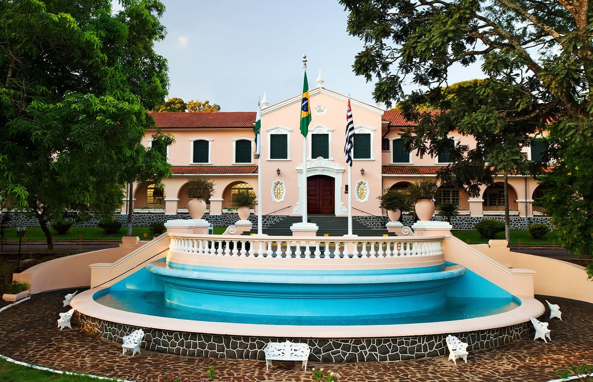 Edifício público com bandeiras e jardim — referência visual a sedes administrativas municipais