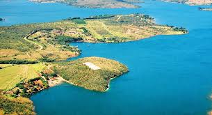 Vista aérea do Lago de Furnas, com águas esverdeadas e vegetação ao redor, na região de Formiga MG.