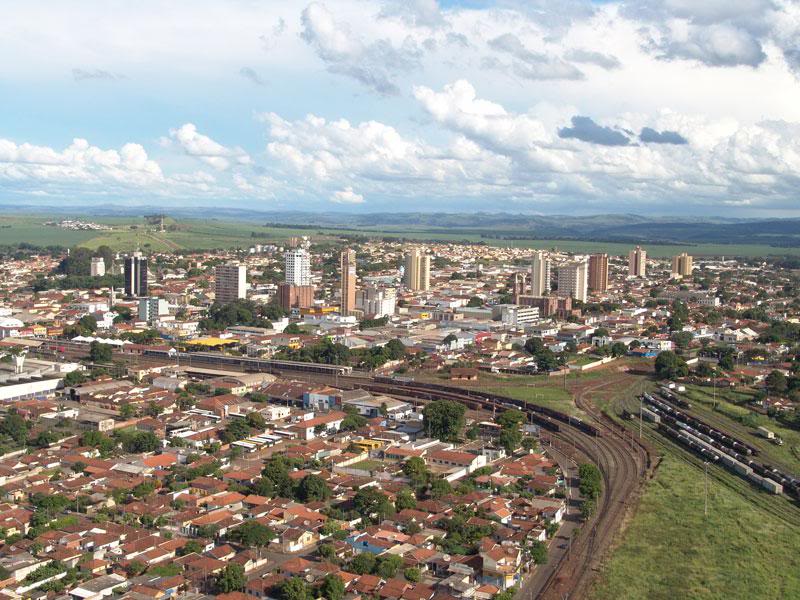 Vista aérea de Ourinhos (SP) com malha urbana, ferrovia e áreas verdes ao fundo