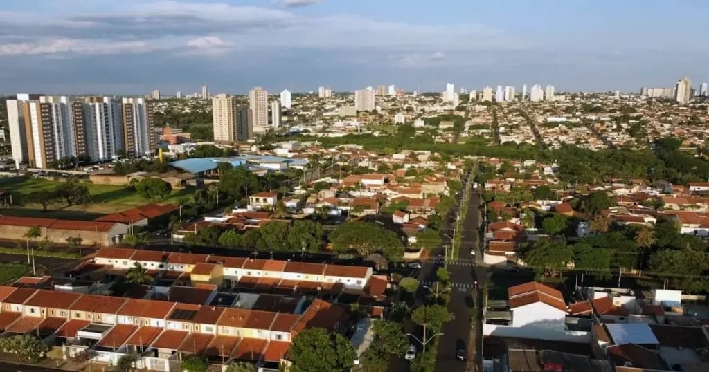 Vista urbana de cidade de médio porte na região Centro-Oeste, com céu azul e áreas residenciais e verdes ao redor