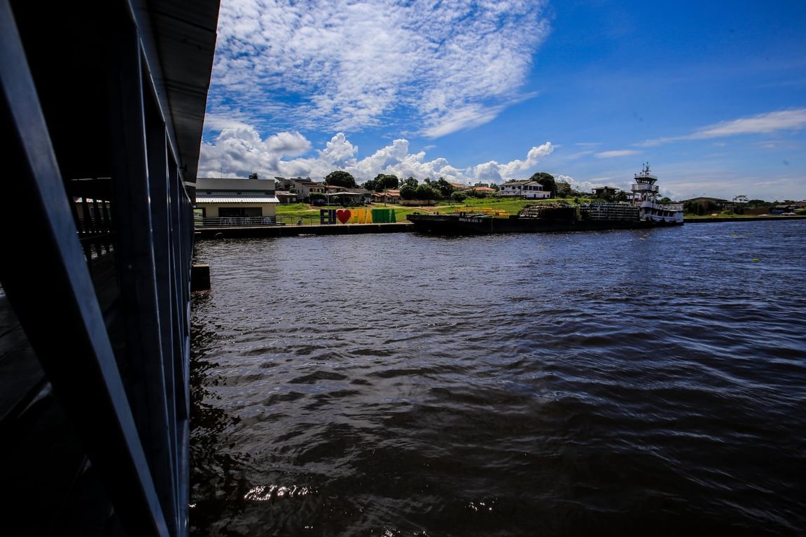 Vista aérea de cidade ribeirinha amazônica com barcos e vegetação, representando Prainha PA
