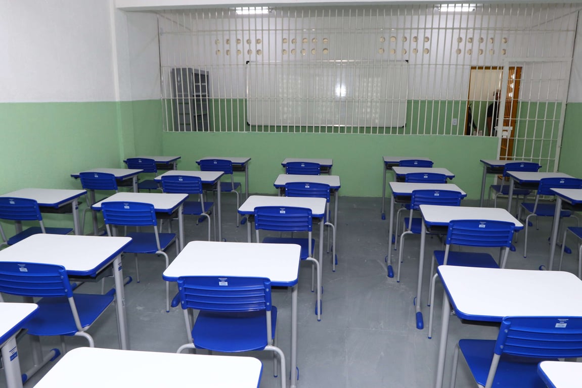 Sala de aula vazia em escola técnica pública, com mesas e lousa.
