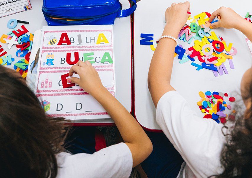 Sala de aula do ensino fundamental com carteiras organizadas e quadro ao fundo, iluminada por luz natural