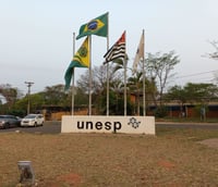 Entrada do campus da UNESP em Bauru, com bandeiras e letreiro da universidade