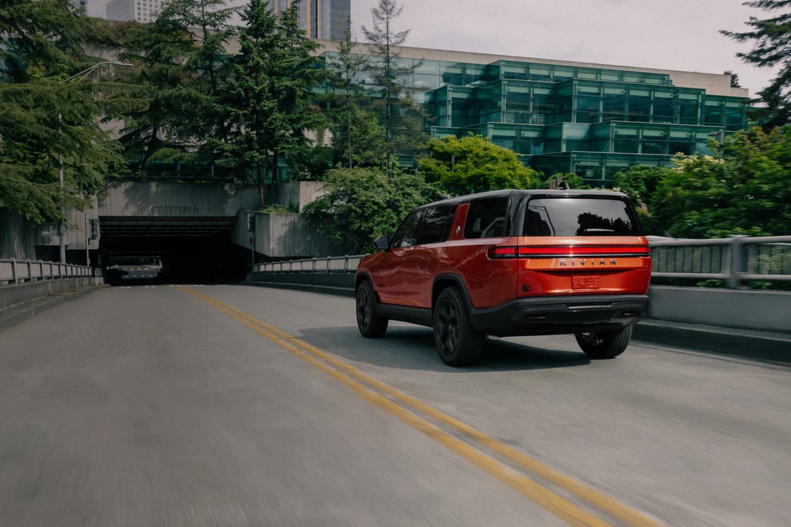 Red Rivian R1S driving down a highway.