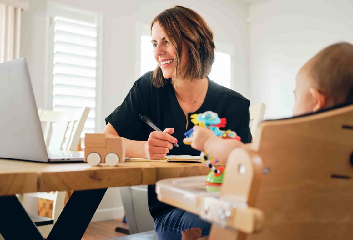 a virtual assistant mom working, baby playing beside her