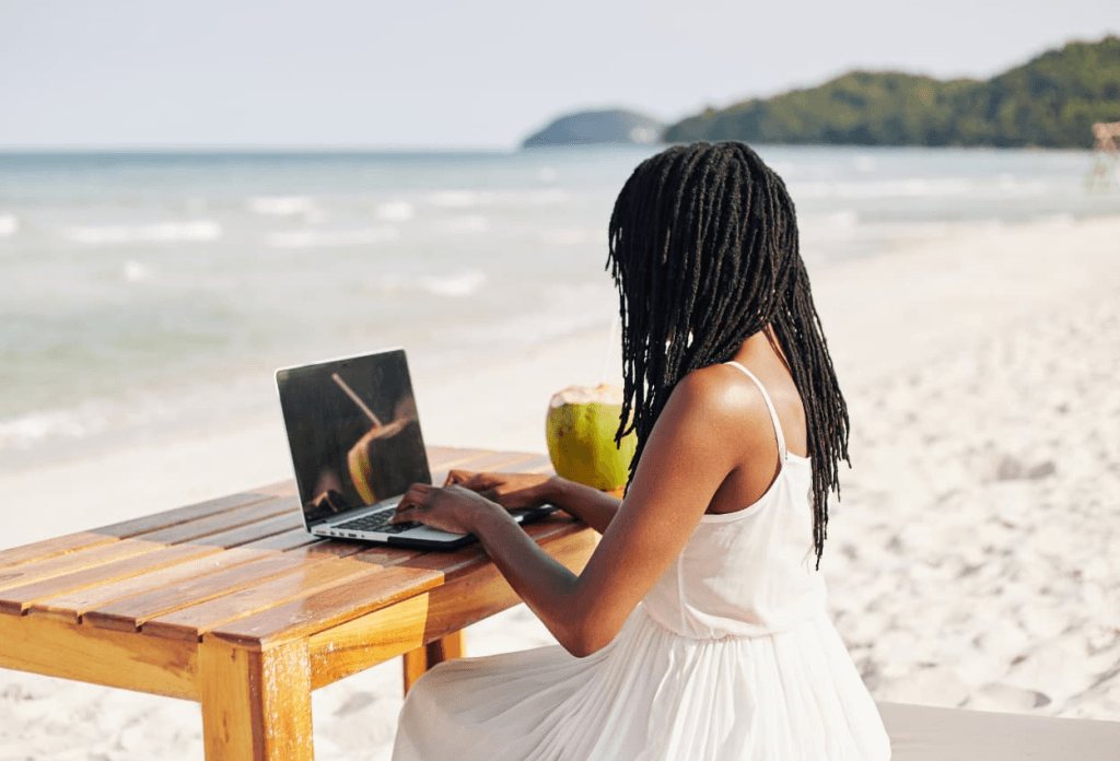 woman in white dress, working remotely at the beach