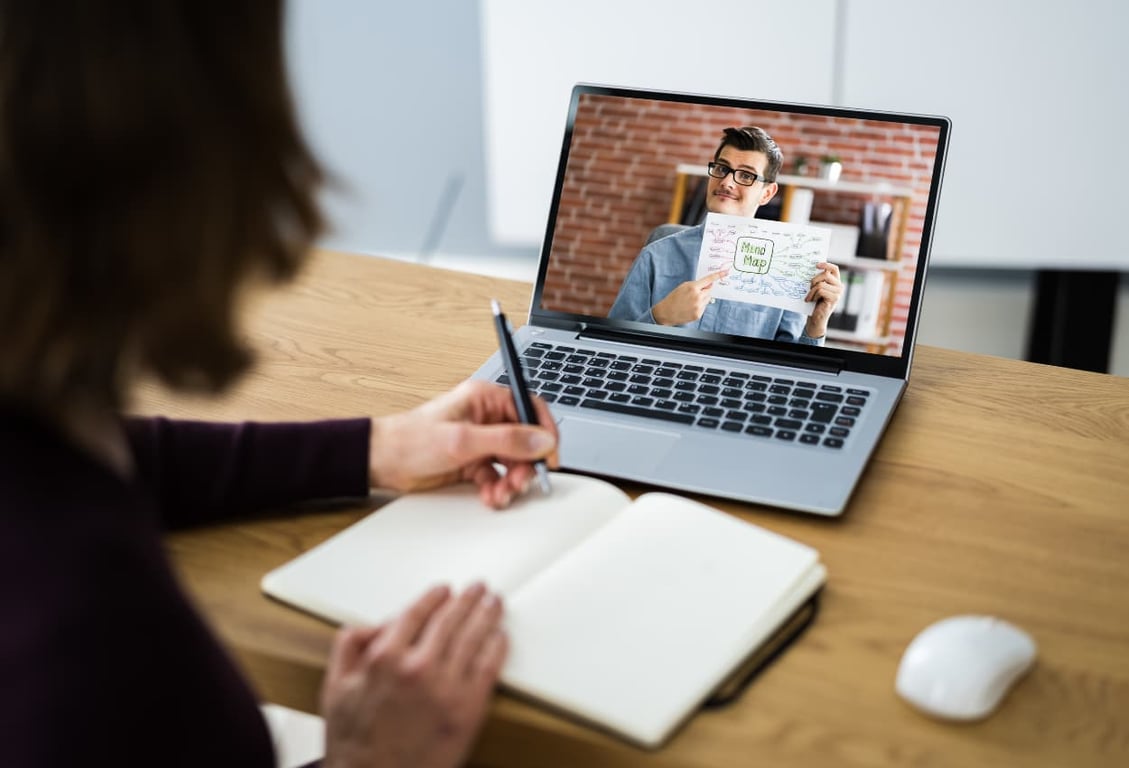 marketers showing examples from the laptop screen, a virtual assistant writing some notes 