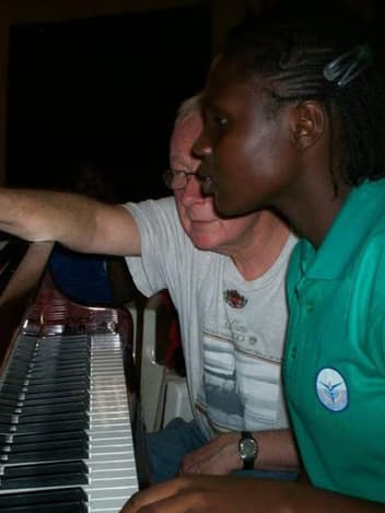 Student learning piano with a volunteer teacher