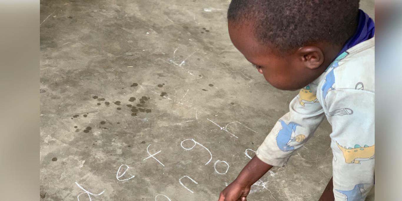 Young boy writing letters in chalk