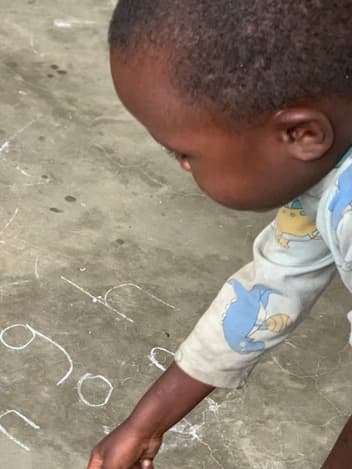 Young boy writing letters in chalk