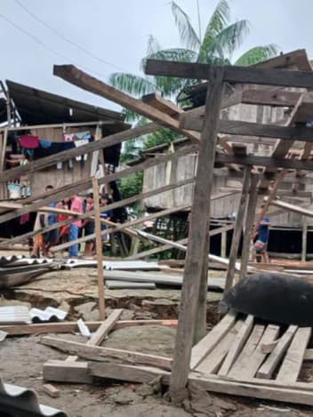 Wooden homes destroyed, timber and corrugated roofing scattered across the ground
