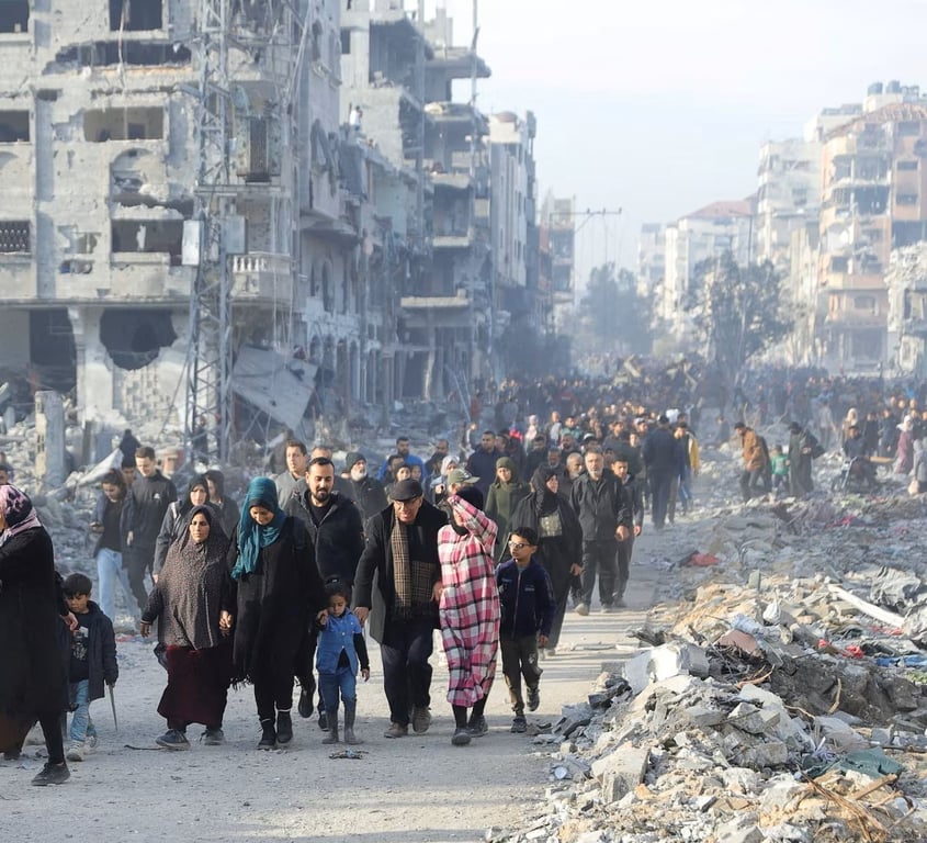 Displaced families walking through a tent camp among rubble in Gaza