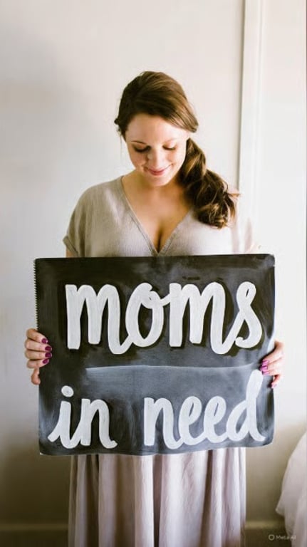 Mother-to-be holding a “moms in need” sign