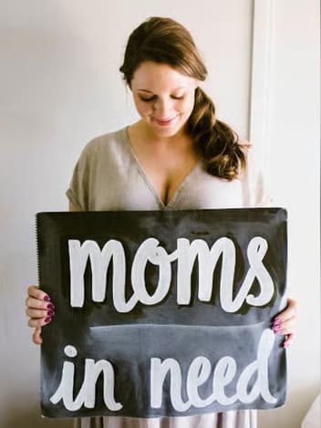 Mother-to-be holding a “moms in need” sign