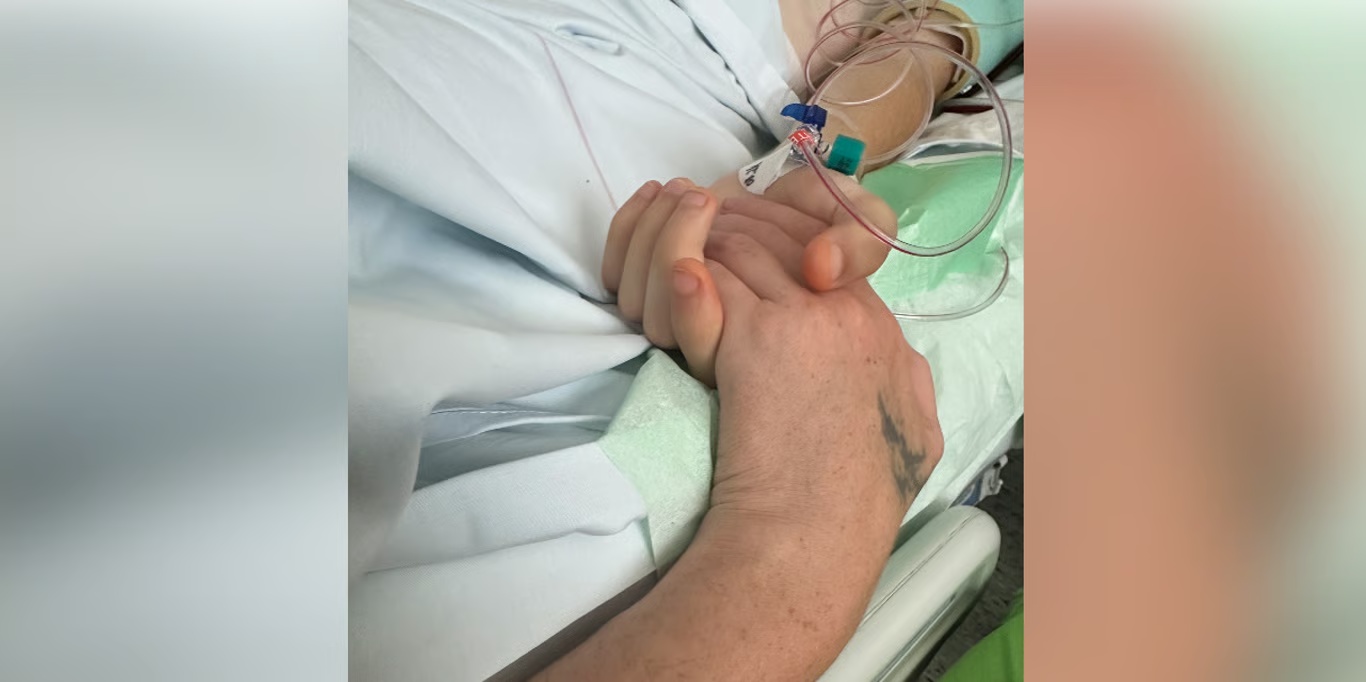 Holding hands at a hospital bedside