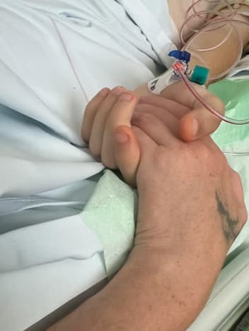 Holding hands at a hospital bedside