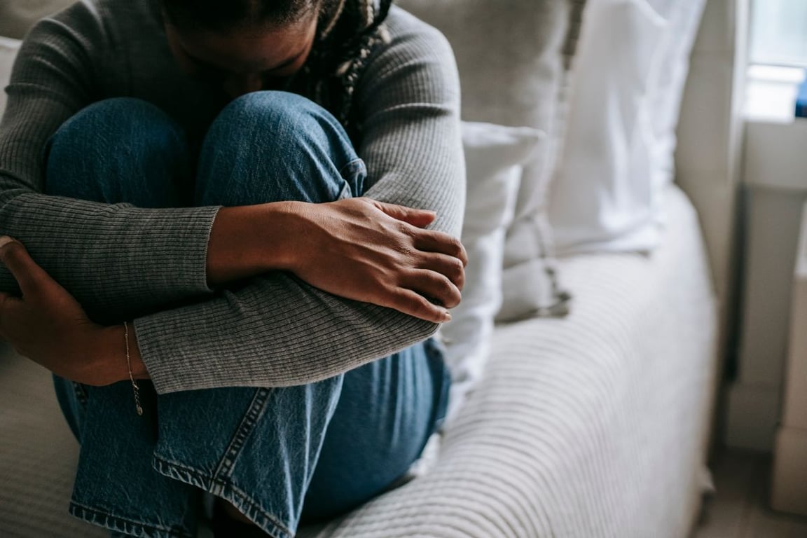 Woman hugging her knees on a sofa