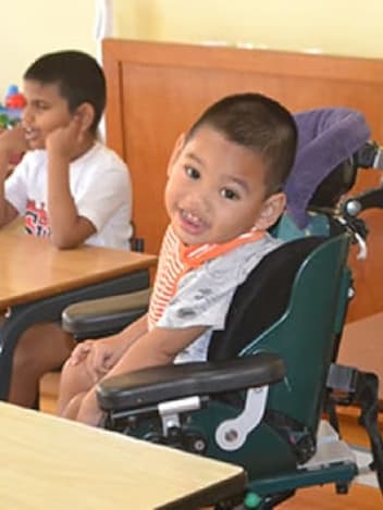 Smiling boy in his wheelchair at school