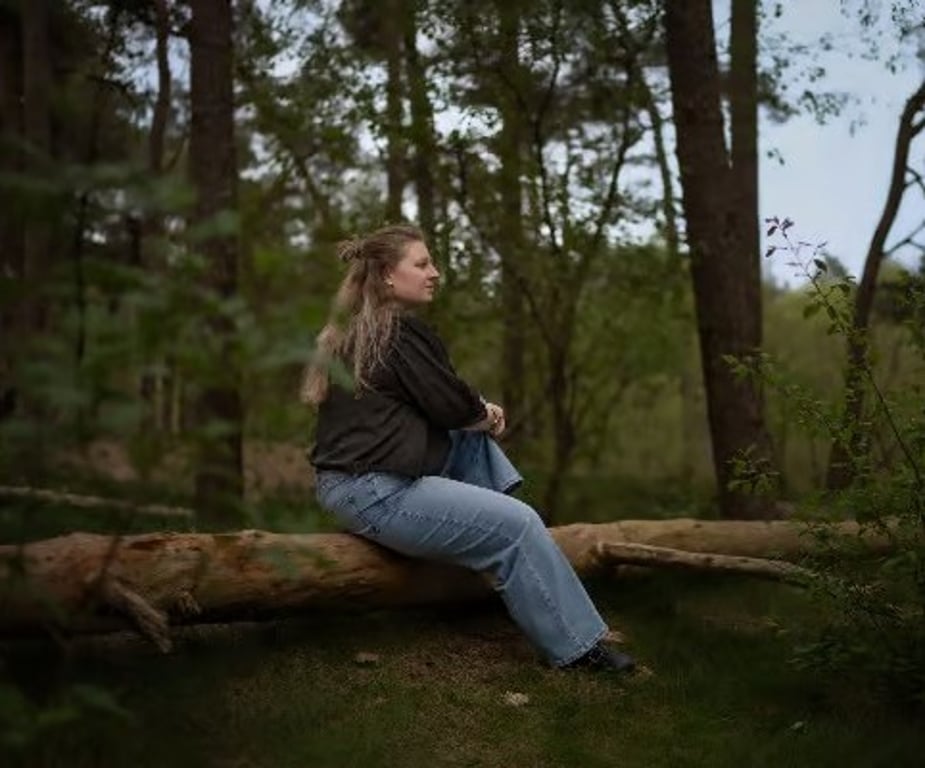 Young woman resting on a fallen tree in the forest