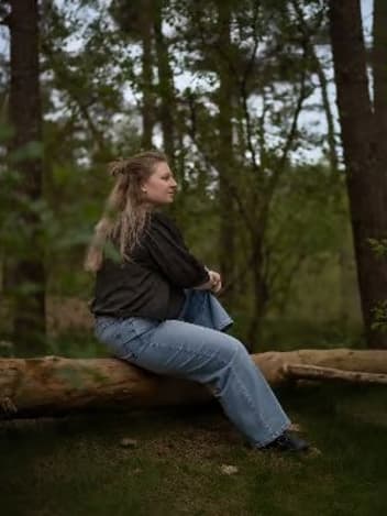 Young woman resting on a fallen tree in the forest