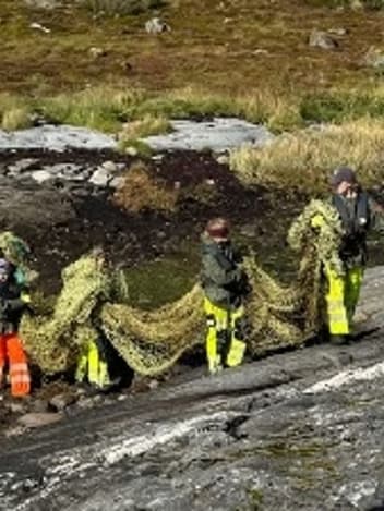 Volunteers hauling waste nets across rocks