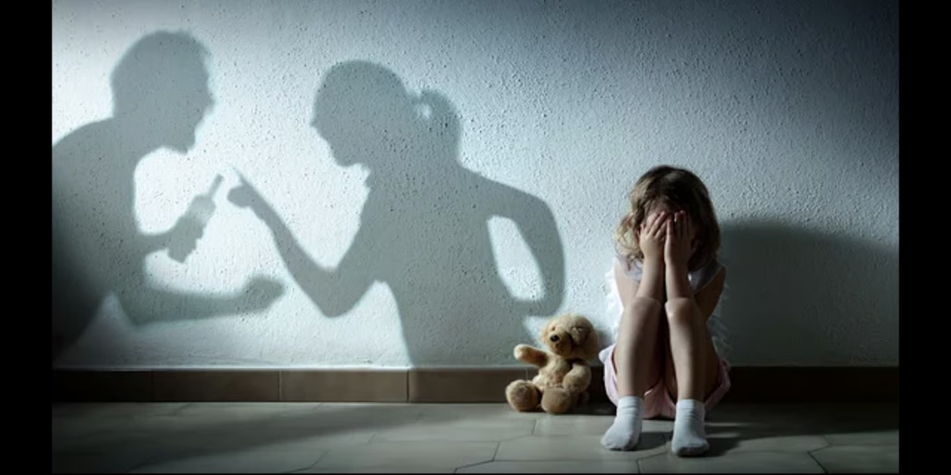 Child hiding her face as shadows of adults argue
